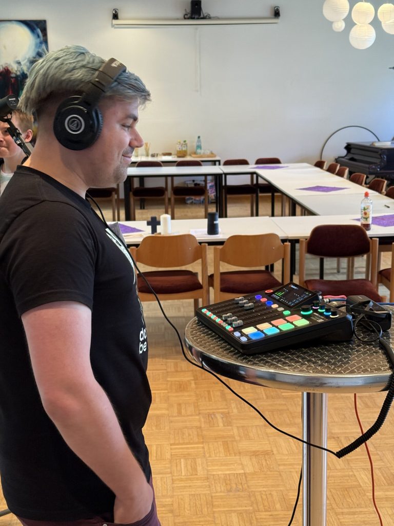 Lars Kokemüller steht mit Kopfhörern an einem Audiomischpult im Werkstattraum.