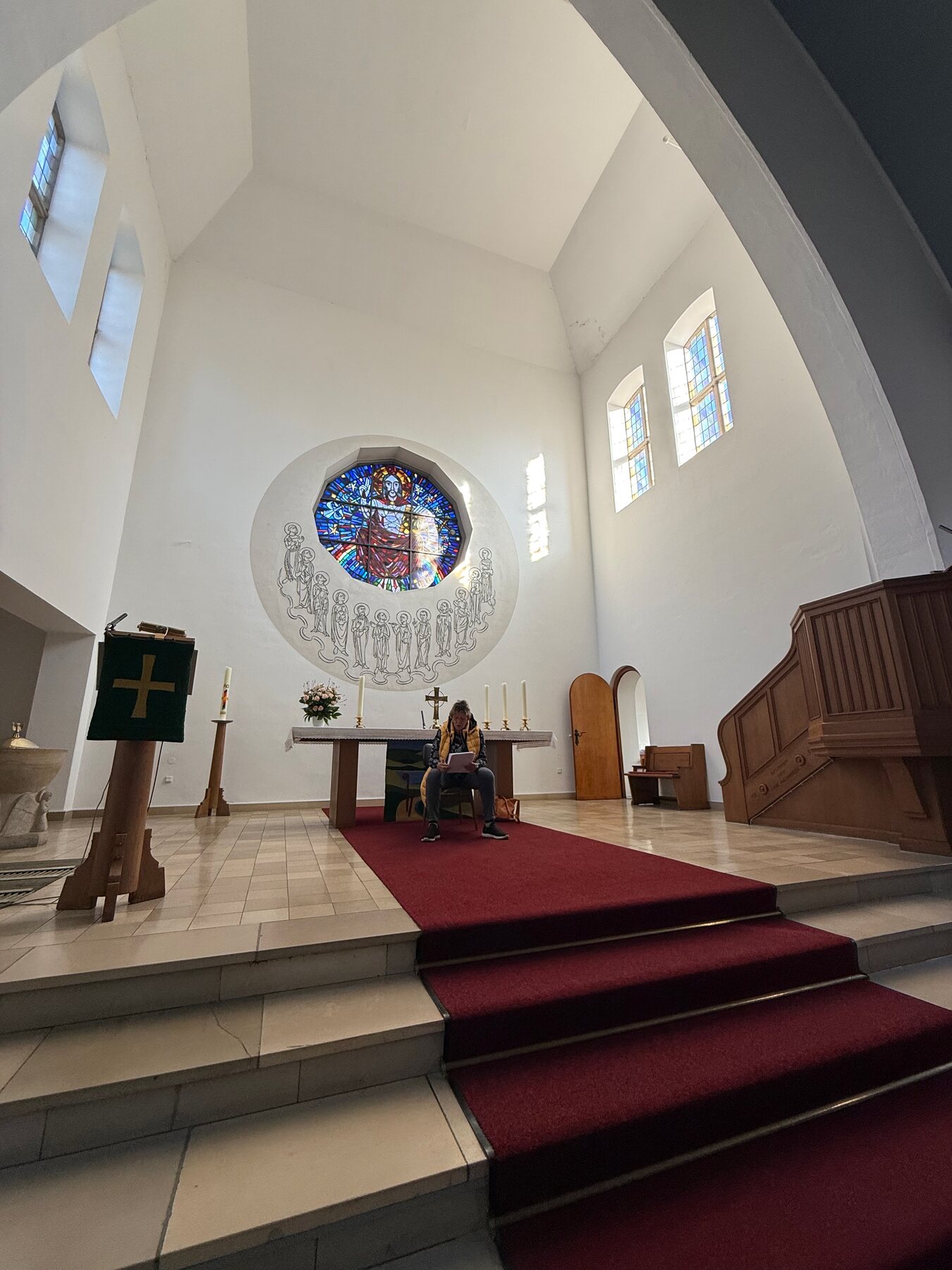 Iris Bretthauer sitzt mit einem Blatt in der Hand vorne in der Apostelkirche.